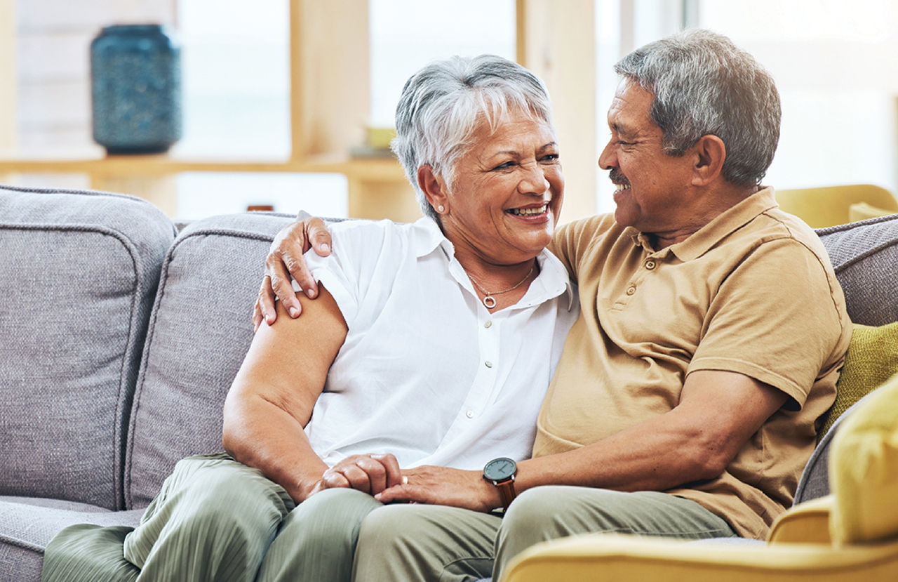 A couple sitting on a couch and smiling at each other
