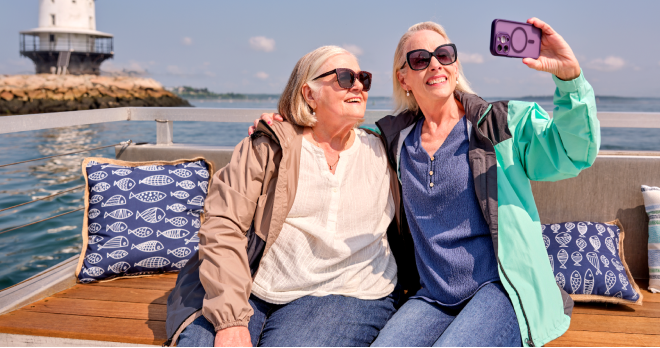 Two women posing for a picture with the ocean behind them.
