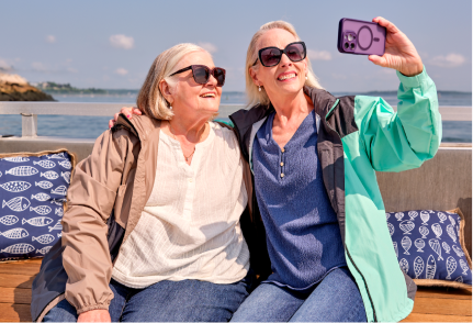 Two women posing for a picture with the ocean behind them.