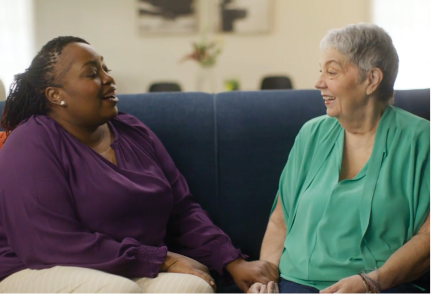 Pam and Ebony are smiling and chatting over shared experiences.